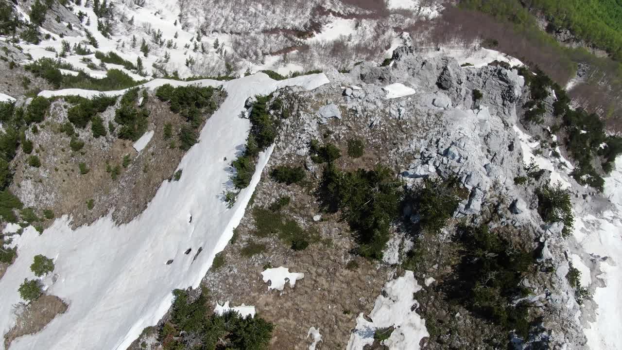 알바니아의 알프스 산맥에서 눈과 바위가 인 산꼭대기 위를 날아다니는 드론 뷰