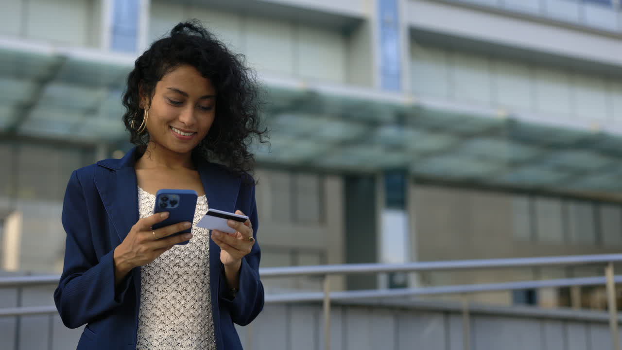 Woman using mobile phone and credit card outdoors