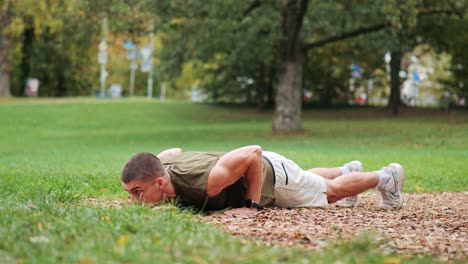 focused young athletic man doing push-ups in training area of public park area