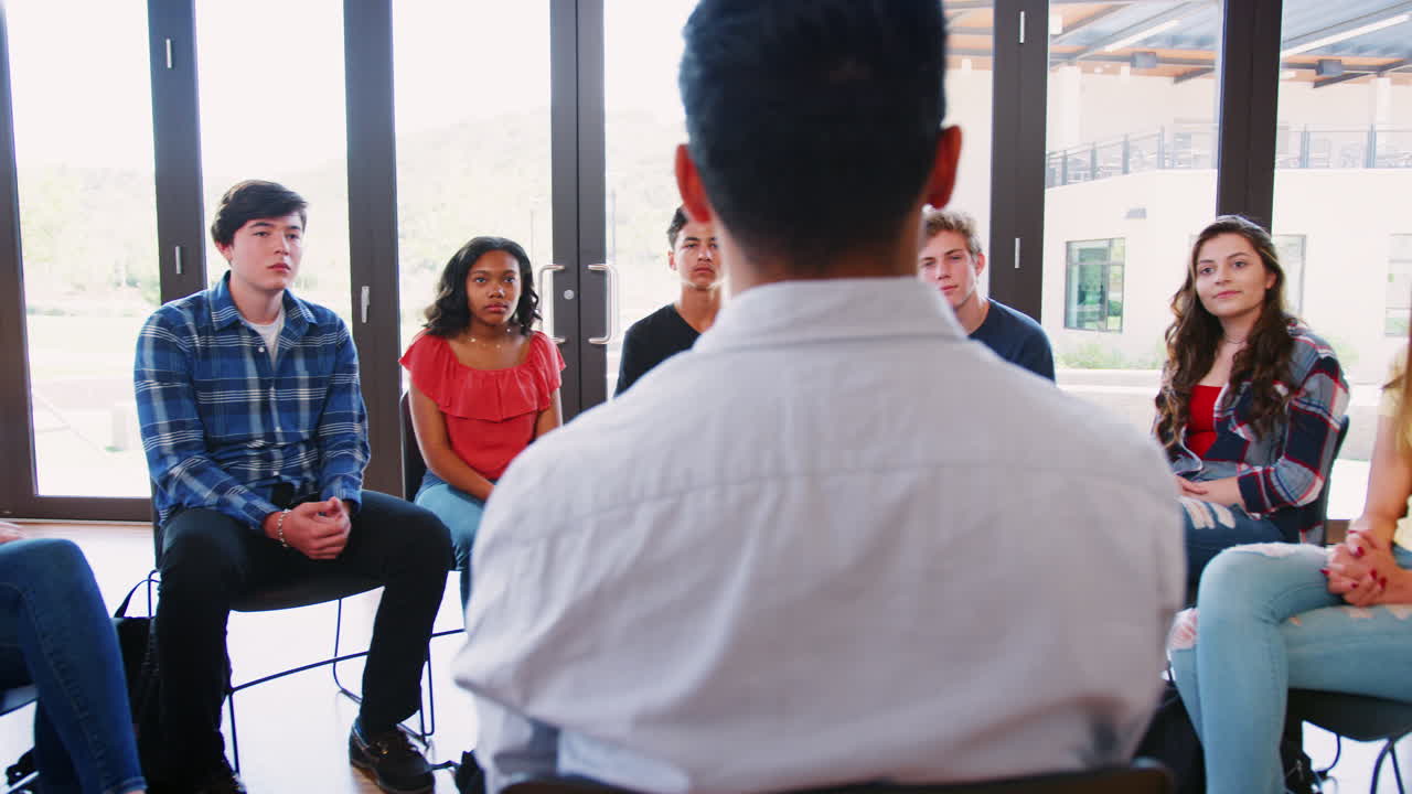 Un tutor uomo che conduce un gruppo di discussione tra studenti delle scuole superiori.