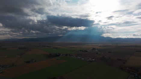 drone aerial shot of sunlight coming through clouds in a farm field