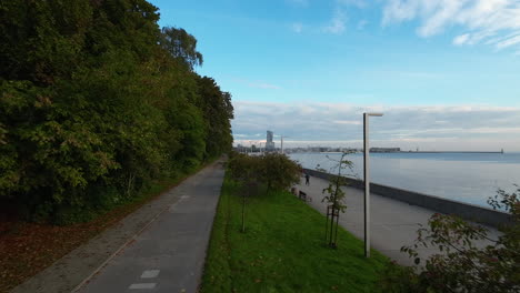 aerial flying over esplanade walkway path with trees in seaside boulevard of gdynia