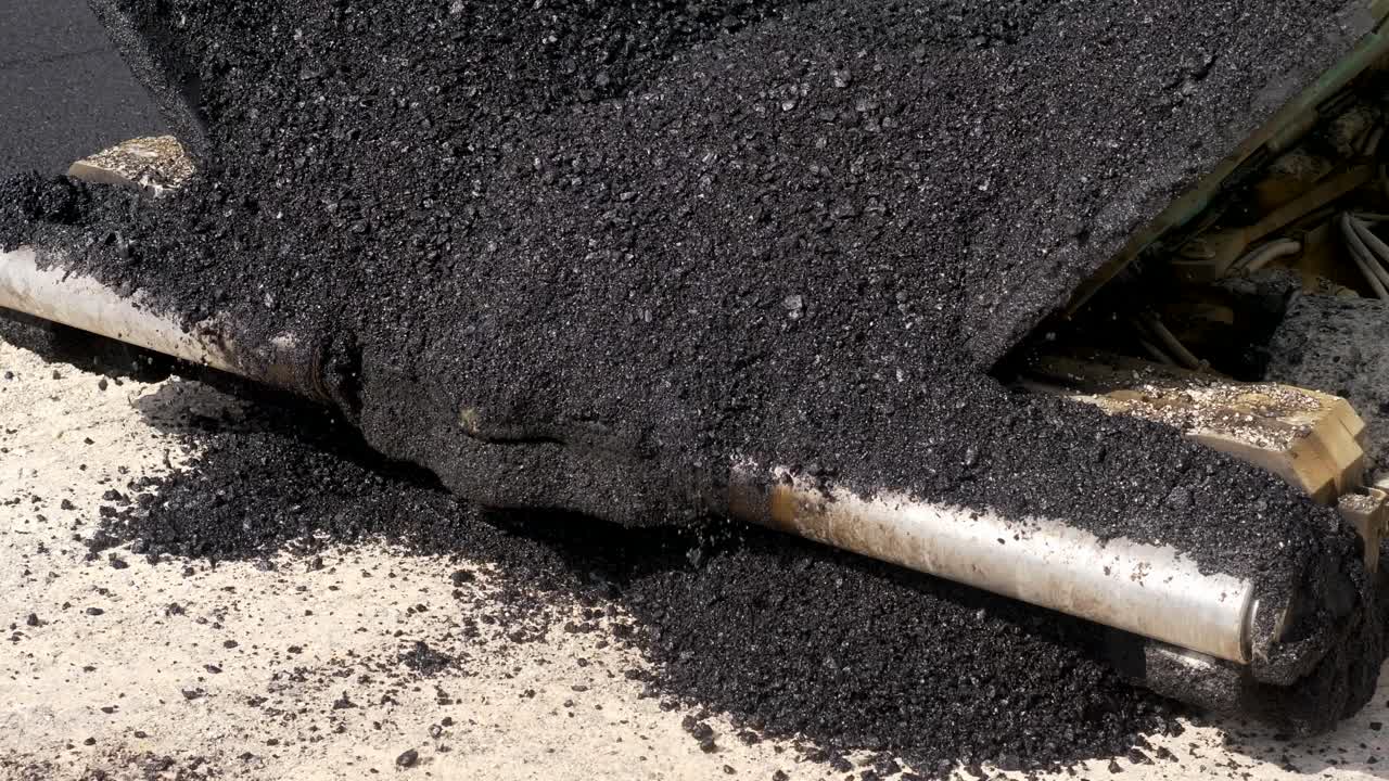 Asphalt paver laying a new road, closeup shot