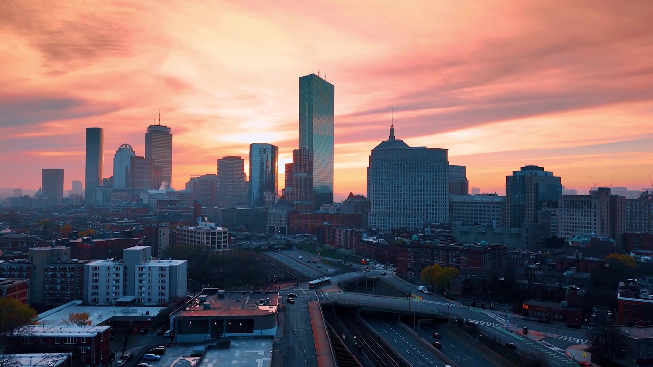 Splendido cielo rosa sopra la città moderna al tramonto. Skyline di Boston, Massachusetts, USA. Il drone si alza sopra l'autostrada a più corsie