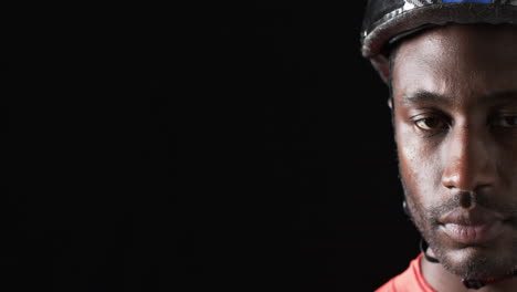 ciclista afroamericano en un casco mira atentamente en un fondo negro, con espacio de copia