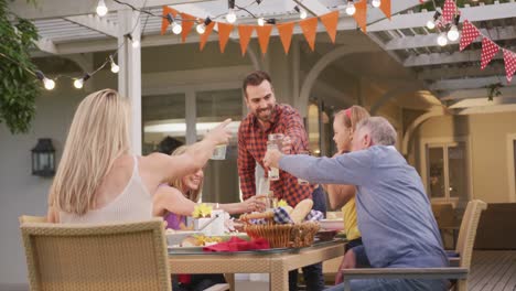 tres generaciones de familia brindando mientras almuerzan al aire libre