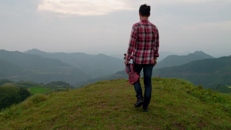 Un-Hombre-Con-Una-Camisa-A-Cuadros-Se-Mueve-Hacia-El-Borde-De-La-Cima-De-Una-Montaña-Sosteniendo-Un-Violín