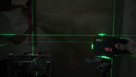 worker using a laser level to project green lines on the wall, ensuring precise alignment in the construction of interior spaces