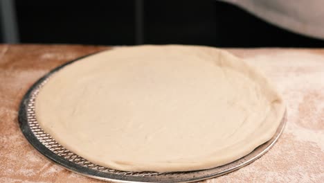 chef preparando pizza con salsa de tomate