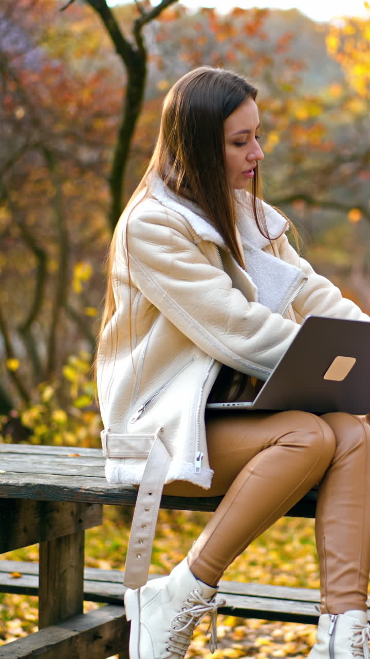 Young attractive woman working in park with laptop. Freelance charming lady have distance work. Vertical video