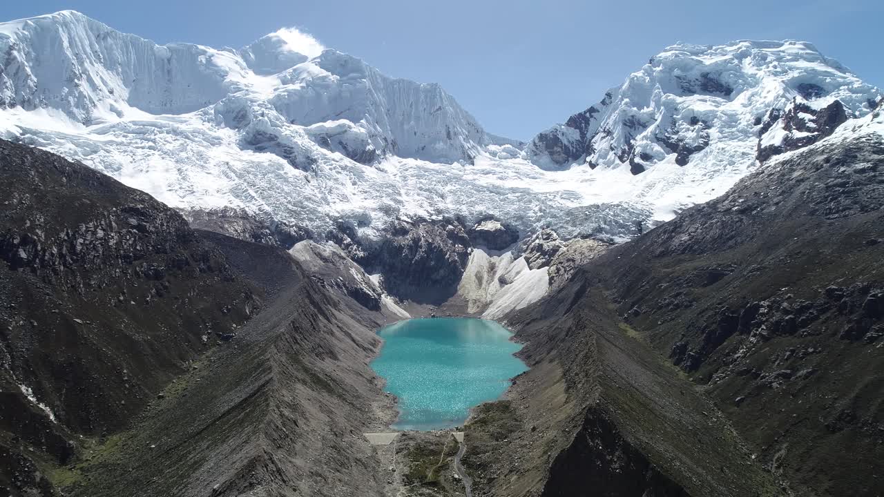 A breathtaking aerial view of a turquoise lake nestled between towering glaciers in the Andes. Ideal for travel, nature blogs, and adventure videography