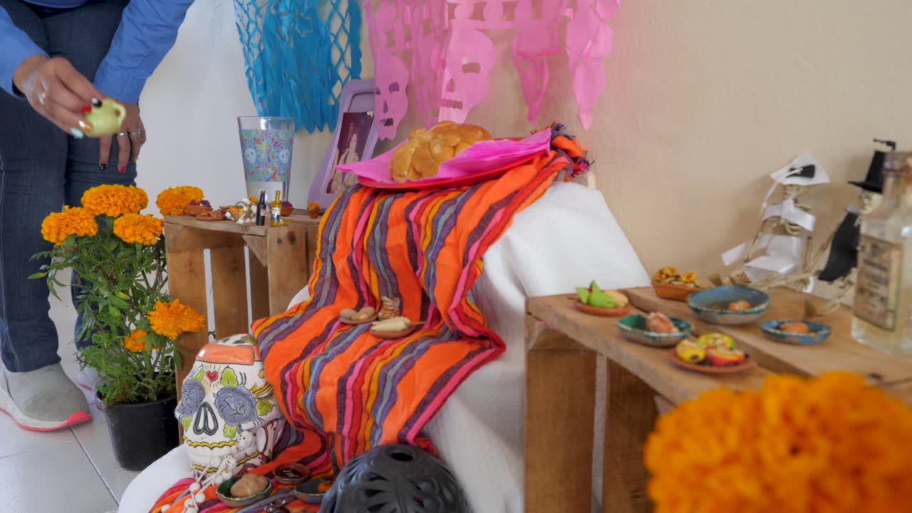 죽은 자의 날을 위한 제단을 장식하기 위해 점토 꽃병을 놓을 장소를 찾고 있는 멕시코 여성