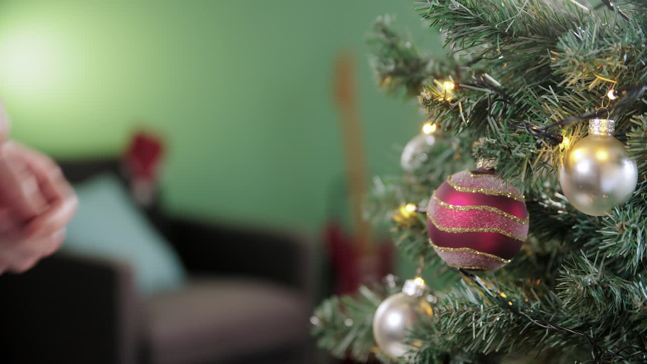 el hombre decora el árbol de navidad con una bola de navidad roja