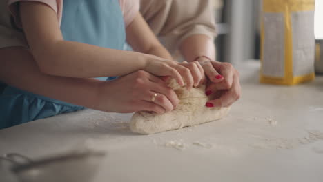 kneading dough in home kitchen mother and daughter are making pastry for bread mom is teaching her child cooking