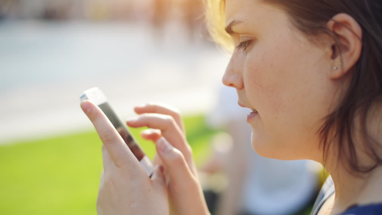 Woman sending text message mobile phone in city park