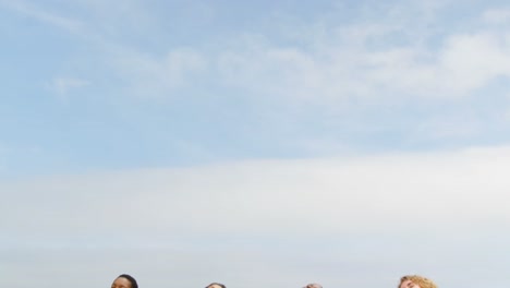 front view of mixed-race female friends relaxing with eyes closed on the beach 4k