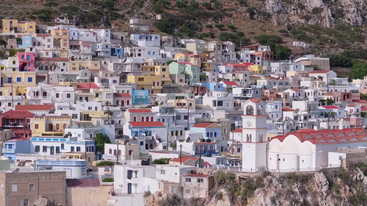 Lateral right drone movement with telephoto lens capturing the vibrant, colorful houses of Menetes Village on Karpathos Island, Greece, highlighting traditional architecture