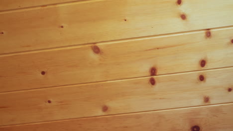close up of wooden room showing vertical wall paneling meeting ceiling corner, featuring light honey toned wood grain, natural knots, and soft lighting that emphasize calm