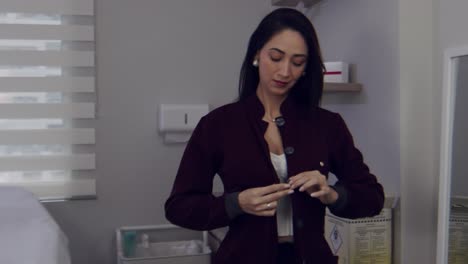 doctora latina poniéndose su bata o bata en su oficina