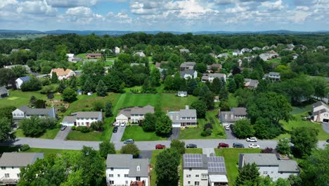 aerial tilt up shot of beautiful american neighborhood with solar panels on roof in natural area with green trees - panorama wide shot