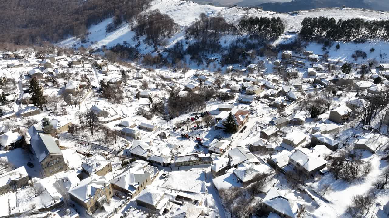 Aerial footage of Nymfaio covered in snow, showcasing traditional stone houses and mountain scenery. Greece