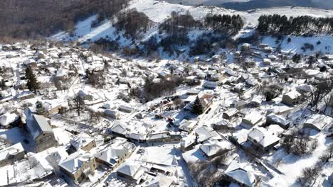 aerial footage of nymfaio covered in snow, showcasing traditional stone houses and mountain scenery. greece