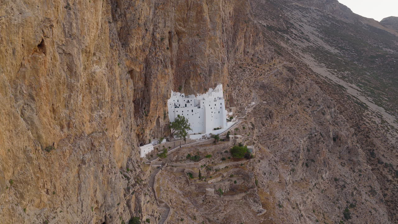 Holy Monastery of the Virgin Mary Chozoviotissa, The Panagia Hozoviotissa Monastery on steep cliffside at sunrise, Amorgos Island, Aerial pullback shot