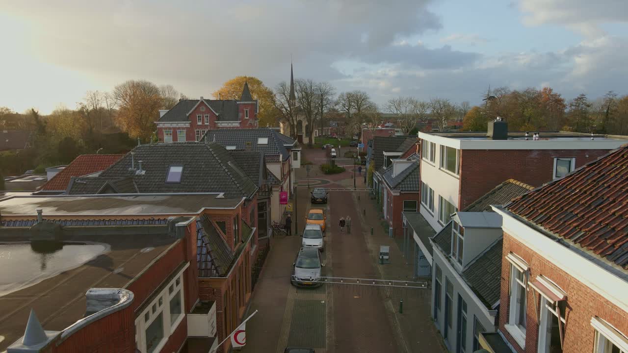 Luchtfoto van een dorpsstraat met wandelende mensen en auto's in Grijpskerk, Groningen, Nederland
