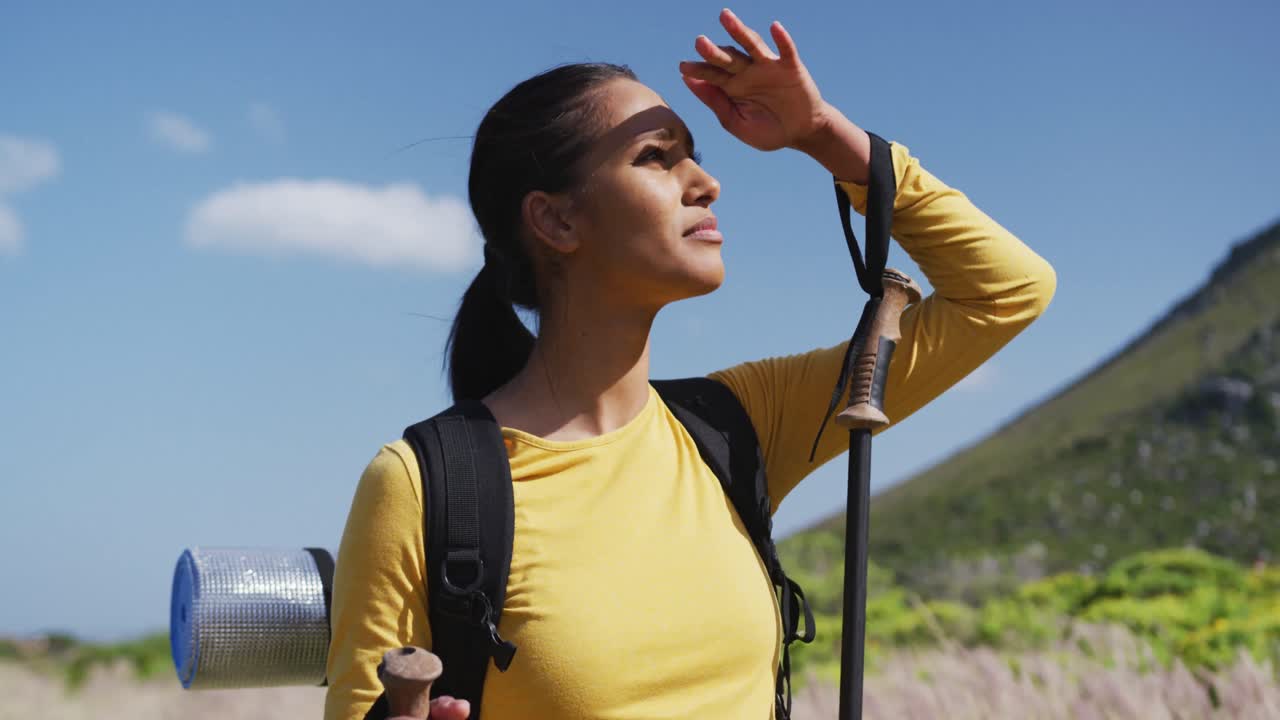 아프리카계 미국인 여성 이 트레킹 스 ⁇  을 들고 산 에서 트레킹 하는 동안  ⁇ 고 있다