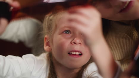 girl looks at processed film with family shots near mother