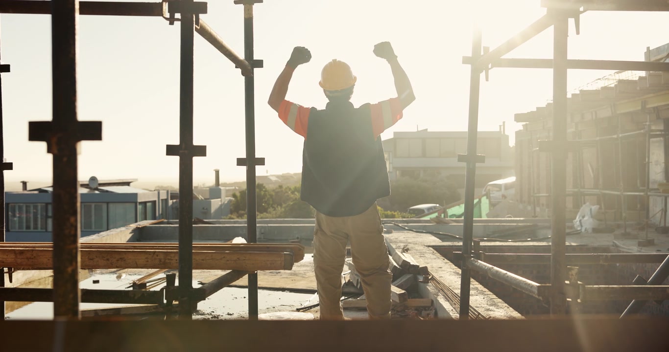 Operaio edile che festeggia il successo nel cantiere al tramonto