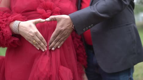 closeup shot of a couple posing and making heart in belly for maternity photoshoot