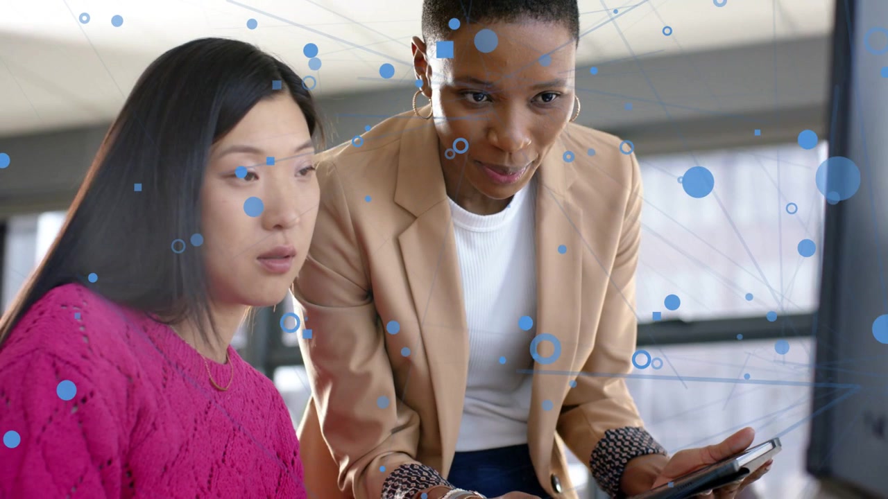 Vertical video: Lead tapping tablet, guiding colleague reviewing IT dashboard with blue net overlay