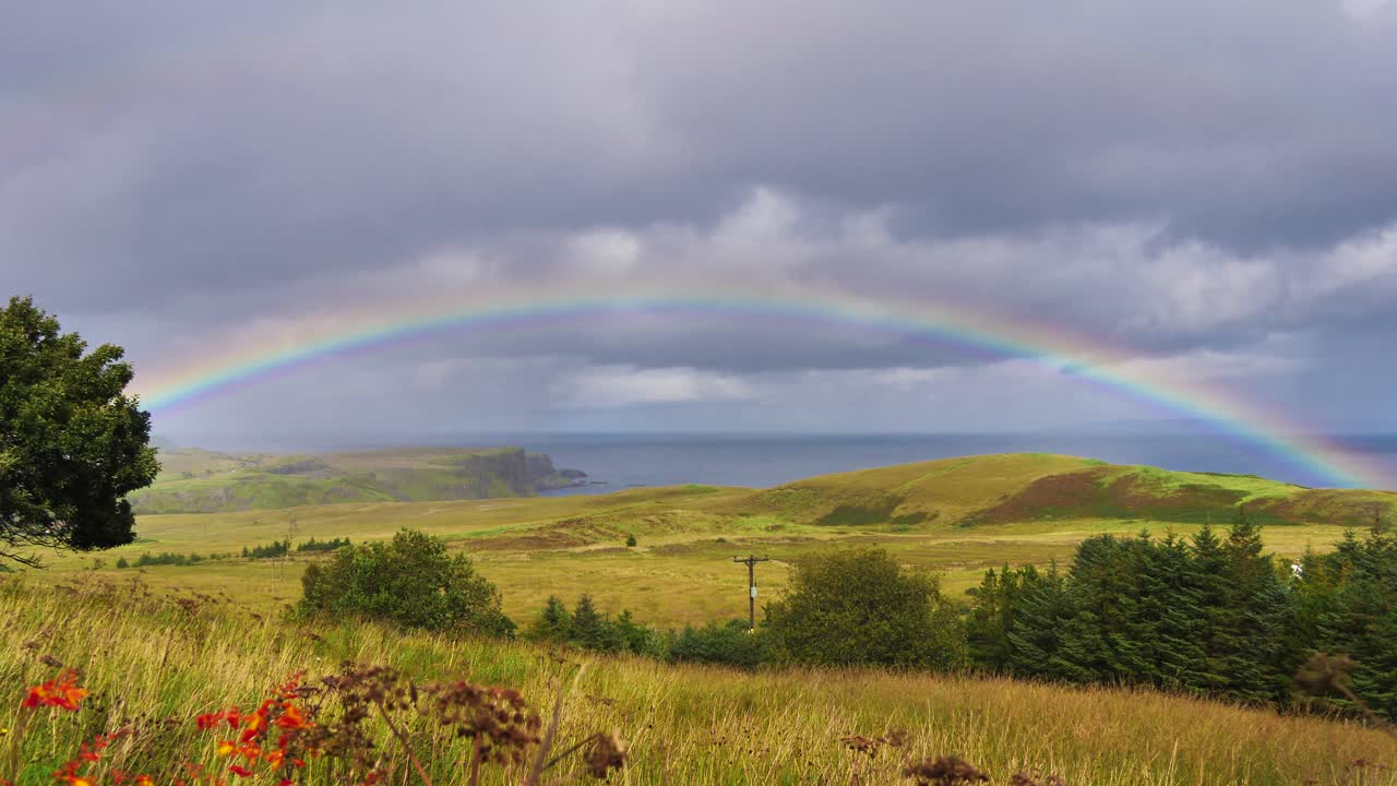 arco iris sobre un campo y acantilados en la isla de skye en escocia en un día tormentoso