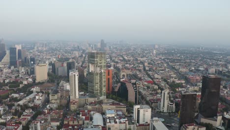 Puesta-De-Sol-Nebulosa-Sobre-Los-Edificios-De-Reforma-Del-Distrito-Del-Centro-De-La-Ciudad-De-México,-Antena