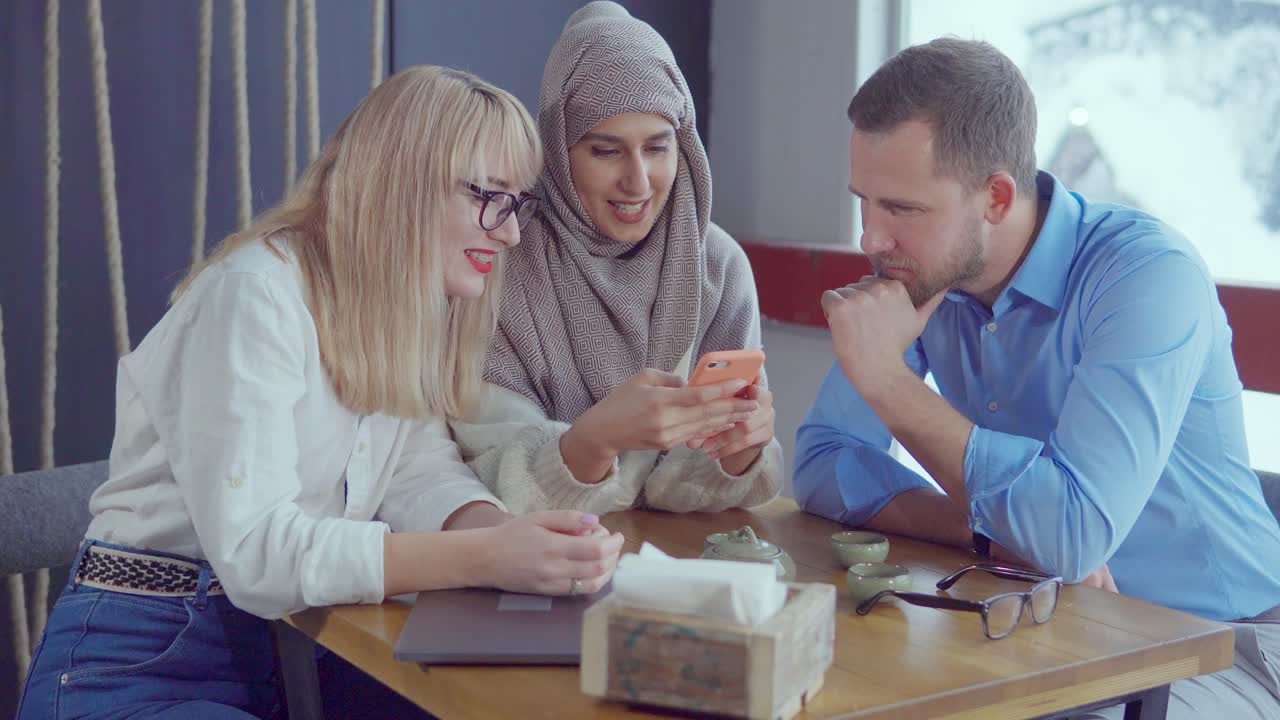 grupo diverso mirando un teléfono inteligente en un café