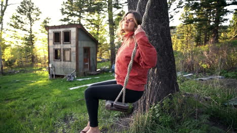 chica de campo yendo gaga en un columpio en red lodge montana woods