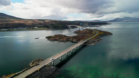 drone descends above skye bridge in scotland as cars commute between island and mainland