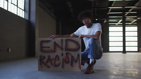 Portrait-of-african-american-man-holding-protest-placard-in-empty-parking-garage