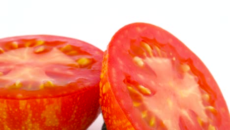 macro shooting. cross section of red globe striped tomato. two halves. slowly rotating on the turntable isolated on the white background. close-up. macro.