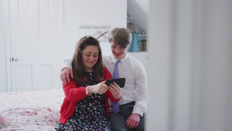 pareja de jóvenes con síndrome de down sentados en la cama usando el teléfono móvil para tomarse una selfie en casa