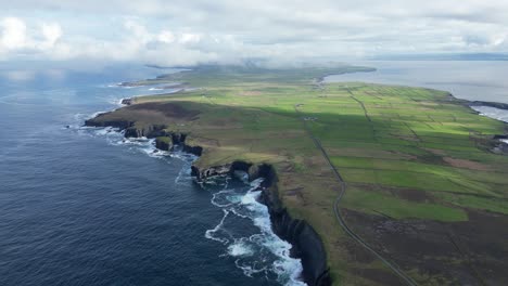 loophead peninsula with dramatic cliffs and lush green fields under a cloudy sky, aerial view