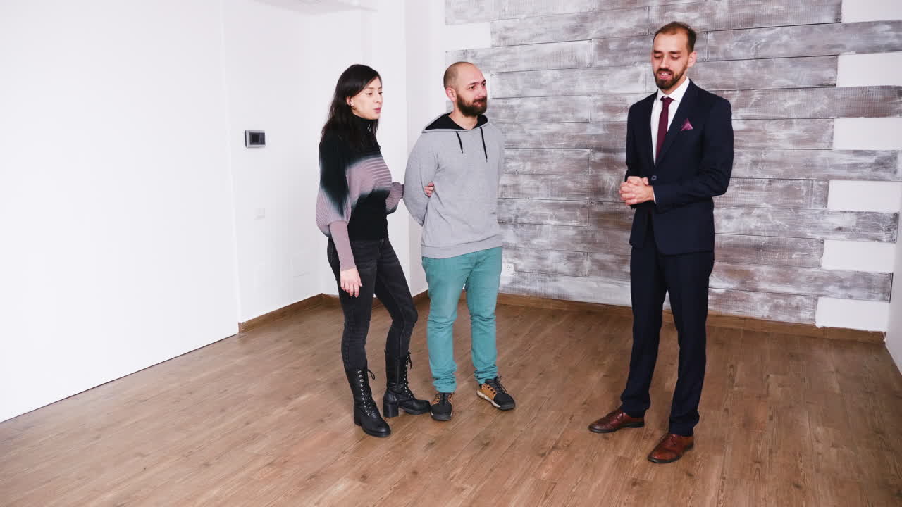 Young couple meeting with real estate agent in empty apartment
