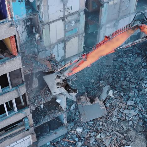 excavator crashing floors of an old building and dusty debris falling down. disassembling of collapsed structures. view from above