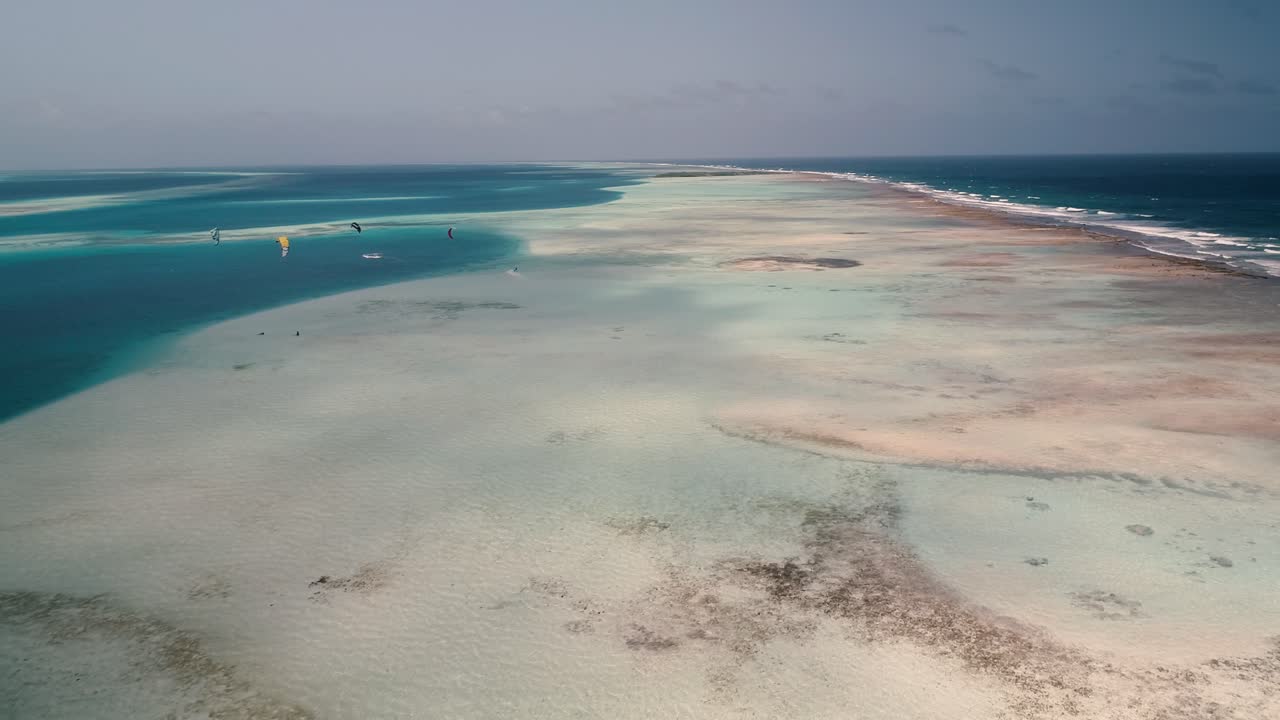 Droneoptagelse: Koralrevsbarriere i Los Roques-arkipelaget med kitesurfere i baggrunden, eventyrrejse