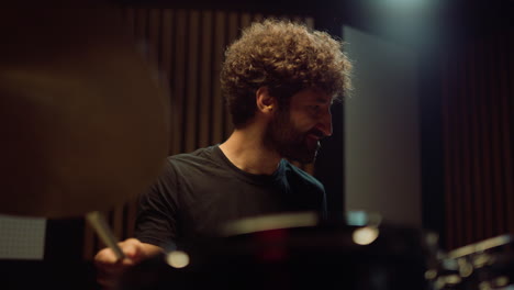 smiling drummer having fun in studio. musician playing on drum cymbals indoor.