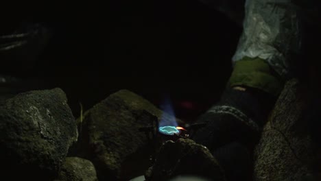 camper's hand in knitted glove lighting up portable stove at night at the campsite. closeup