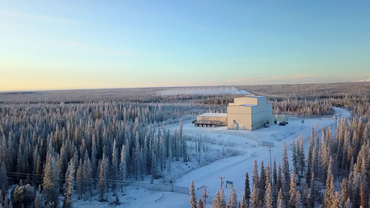 Aerial, drone shot, panning over a road, towards the HAARP Alaska facility, on a cold and sunny, winter day, in Gakona, USA