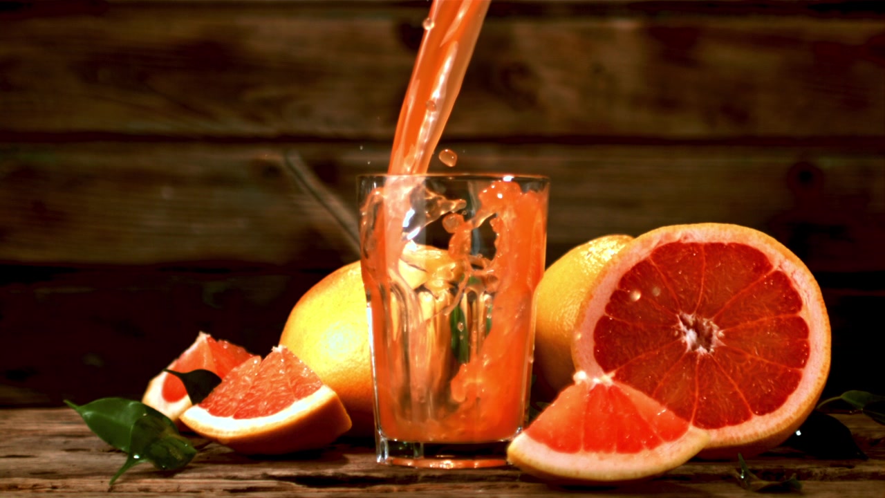 Succo di pompelmo fresco che si versa in un bicchiere al rallentatore