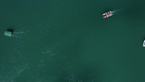 bird's eye truck left aerial drone shot following small tourist transport ships from the tropical restinga beach sailing towards the coastal town of barra do cunhaú in rio grande do norte, brazil